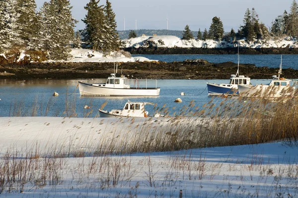 Fishing boats stay safe in snow covered Owls Head Harbor after a snowstorm in mid coast Maine.