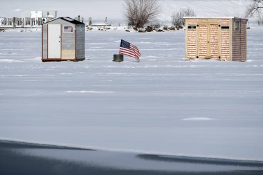 Amerikan bayrağı görüntüler arasında iki buz balıkçı kulübeleri yakın göl 