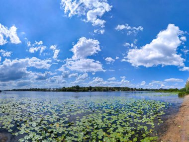 Ukrayna, Kyiv 'deki kumsal Dinyeper Nehri' nde bahar panoramik manzarası. Mavi güzel bulut gökyüzü berrak suya yansıyor. Doğanın sakin tefekküre dalması. Huzur ve sessizlik. Işık bulutları atmosferik görüntüyü sorunsuzca doldurur. Güneş banyosu ve yüzme.