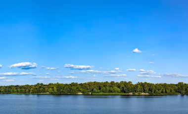 Nehrin yukarısında bulutlar var. Suyun yüzeyinde buhar kabarcıkları uçuşuyor. Gökyüzü ve dalgalarla dolu bir manzara. Tatlı su rezervleri. Su zambakları yüzeyde büyür. Mavi gökyüzü ile gün.