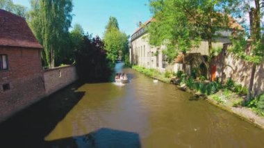 Brugge/Bruges, Belçika Reie Nehri boyunca güneşli hava ve güneş üzerinde mutlu sallayarak turist turist tekne