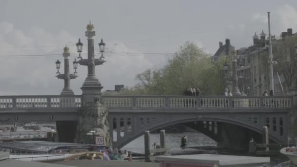  Amsterdam/Nizozemsko-duben 2019: turistické čluny a most poblíž hlavního Gracht v Amsterdamu (plochý profil)