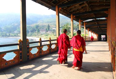 İki genç rahipler platolarının Mocchu Bazam üzerinde yürüme: antika ahşap köprü Punakha Dzong manastır veya Pungthang Dewachen Phodrang Butan,