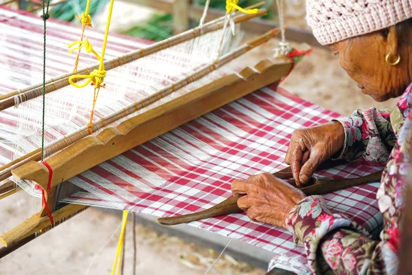 stock image April 07, 2018 - Mahasarakham province , THAILAND : Old Thai woman using traditional household weaving machine or hand weaving loom for weaving the cloth.