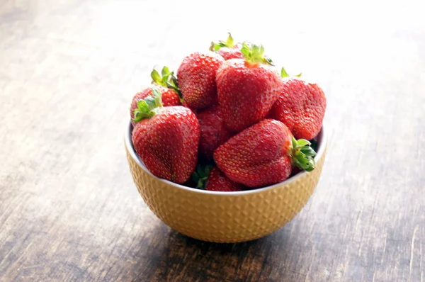 在木桌上的碗里放新鲜的草莓。在木桌上的碗里放新鲜的草莓。素食主义, 纯素食。健康的概念, 适当的营养, 饮食. 免版税图库图片