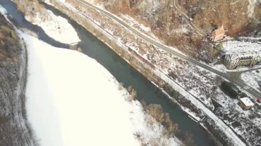 Poprad Parkı 'ndaki Poprad Nehri' nin üzerinden geçen yolcu treninin hava görüntüsü bulutlu, kış günü.