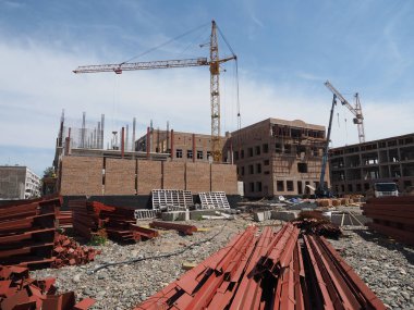 Hangi yeni tuğla bina yüksek vinçler ve yerde inşa inşaat alanında metal öğeleri ve yapı malzemesi vardır