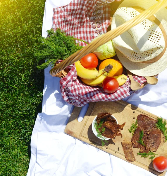 Çimenlerin üzerinde parkta piknik: sağlıklı gıda ve aksesuarları, üstten görünüm