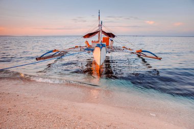 Kıyıda bir balıkçı teknesi, güne başlamak için bekliyor.