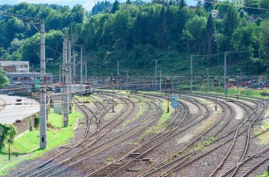 Tren raylarını, vagonları ve arka plandaki istasyonu birleştiren ve kesişen bir tren istasyonu görüntüsü