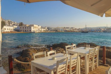 Mykonos tipik Yunan Restoran eski şehir, Cyclades Island, Yunanistan tabloları ile sandalye. Panoramik marina, kumsal ve karakteristik beyaz evler.