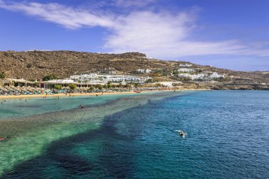 Yaz. Mykonos: Paradise beach (Kalamopodi), Yunanistan. Kristal berraklığında su ve mavi gökyüzü güneşli. Mykonos kesinlikle en ünlü plaj cennettir: ince kum ve zümrüt yeşil su.