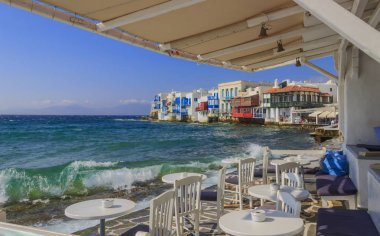 Mykonos Adası ünlü resimsel Küçük Venedik manzarası. Dalgalar bar ve restoran eski şehir, Kiklad Adaları, Yunanistan sıçramasına. Tipik Yunan restoranı tabloları ile sandalye.