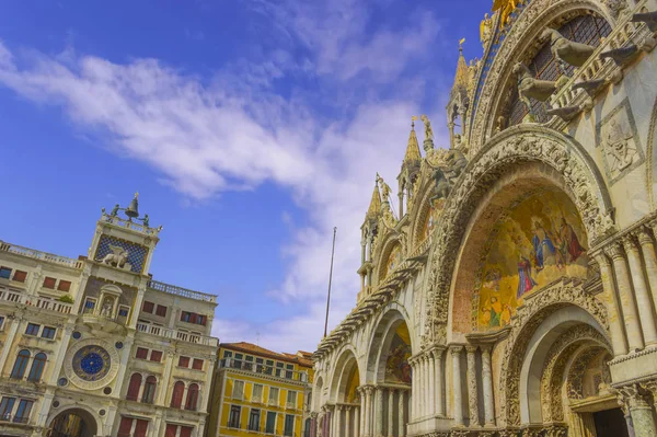 The Patriarchal Cathedral Basilica of Saint Mark and The Clock Tower at the Piazza San Marco - St Mark's Square, Venice Italy. The exterior of the west facade of Saint Mark's Basilica.