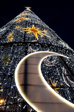 Bir Noel ağacının dikey alçak açılı görüntüsü. Yıldızlı ve koyu arkaplanlı yarım ay desenli.