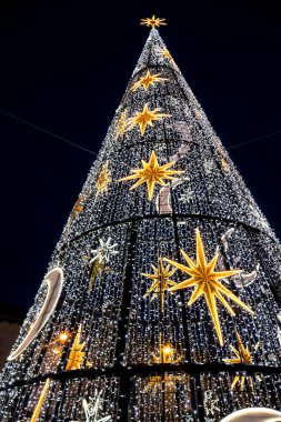 Bir Noel ağacının dikey alçak açılı görüntüsü. Yıldızlı ve koyu arkaplanlı yarım ay desenli.