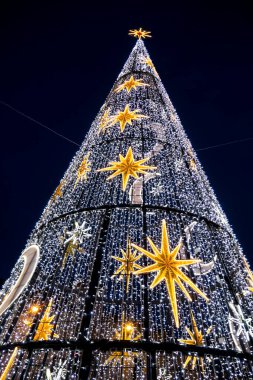 Bir Noel ağacının dikey alçak açılı görüntüsü. Yıldızlı ve koyu arkaplanlı yarım ay desenli.