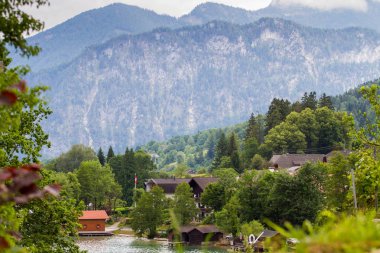 Attersee 'nin göl kenarında sakin bulutlu bir gün ve yazın sonlarında arka planda dağlar. Attersee Gölü Avusturya Salzkammergut 'unda