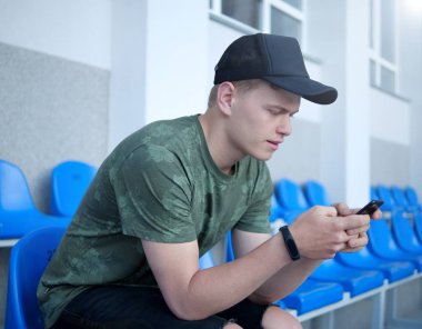 Genç adam telefonunu kontrol ediyor.