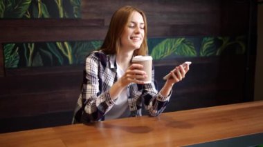 Güzel bir kız telefonda yazıyor ve kahve içiyor