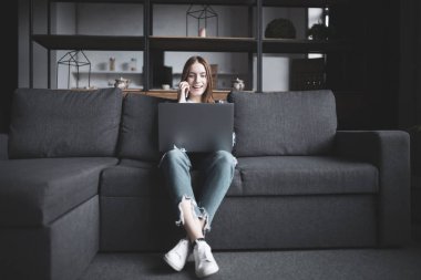 Dizüstü bilgisayar kullanarak ve fon üzerinde konuşmak mutlu genç güzel kadın