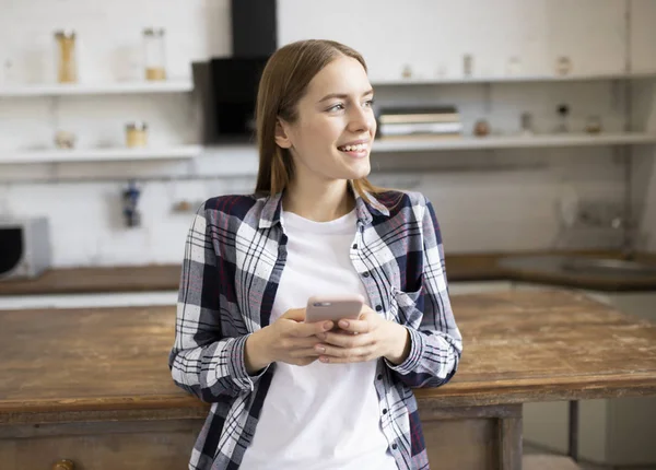 Menina bonita sorri e usa seu telefone — Fotografia de Stock