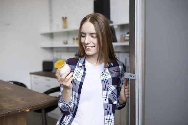 Красивая девушка берет йогурт из холодильника. Атлетическая женщина на — стоковое фото