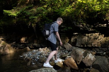 Dağların arkasında büyük bir sırt çantası olan genç bir adam.