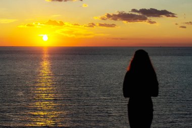 Güneş doğarken sahilde tutan sadık kadın silueti bir arka ışık açık görünüm