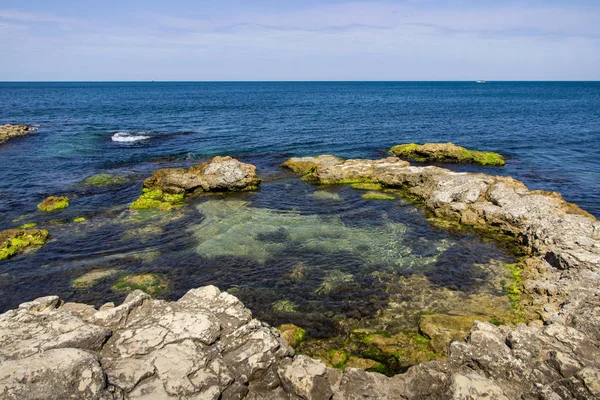 Błękitne niebo i morze z kamieniami w tle zachód słońca scenerii. Zachód słońca żwirowa plaża morska wśród skał i kamieni. — Zdjęcie stockowe