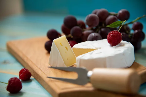 Sýr camembert s malinami a hrozny na stole — Stock fotografie