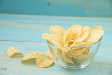 Mavi ahşap zemin üzerine kase gevrek patates cipsi