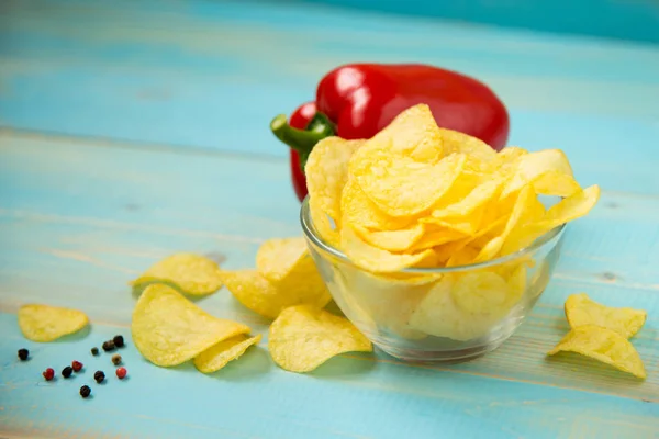 Potato chips in bowl on a blue wooden background