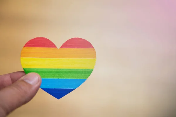 Concepto LGBT. Mano sobre fondo azul sosteniendo el arco iris corazón — Foto de Stock