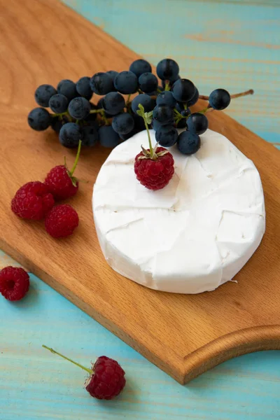 Cheese camembert with raspberries and grapes on table — Stock Photo, Image