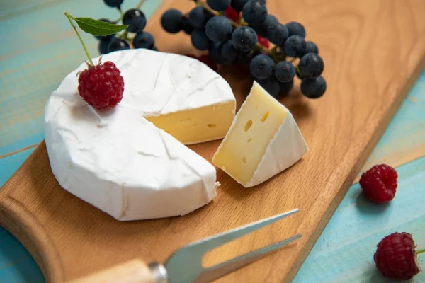 Сыр камамбер с малиной и виноградом на столе — стоковое фото