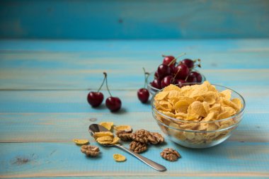 Lezzetli mısır gevreği witt ceviz ve kiraz mavi zemin üzerine cam kapta. Mısır gevreği, kopya alanı. Sağlıklı kahvaltı-Mısır gevreği ve ceviz, kiraz 