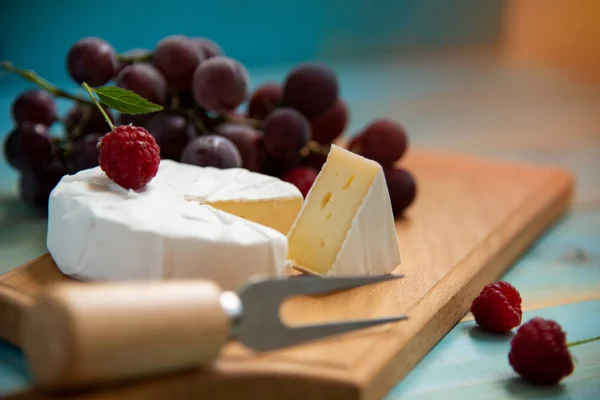 Sýr camembert s malinami a hrozny na stůl — Stock fotografie