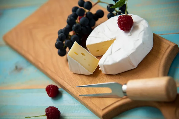 Camembert de queijo com framboesas e uvas na mesa — Fotografia de Stock
