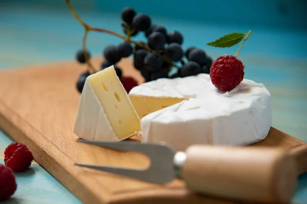 Camembert de queijo com framboesas e uvas na mesa — Fotografia de Stock