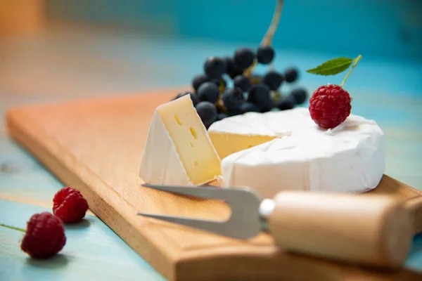 Camembert de queijo com framboesas e uvas na mesa — Fotografia de Stock