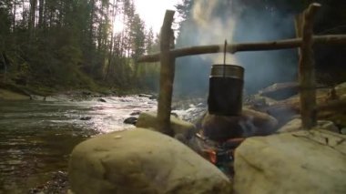 Kamp ateşi üzerine tencerede yemek yiyecek