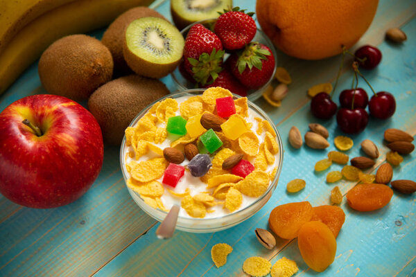 Tasty cornflakes with milk and fruits in glass bowl
