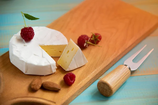 Сыр камамбер с малиной и орехами на столе — стоковое фото