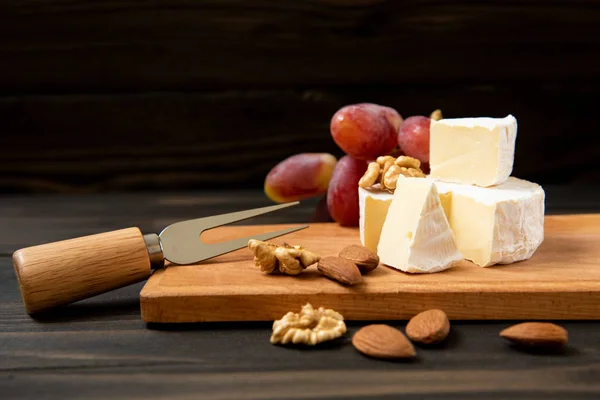 Сыр и виноград на темном фоне — стоковое фото