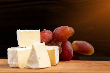 Peynir ve karanlık bir arka plan üzerinde üzüm