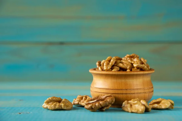 Nueces sobre mesa rústica azul en cuenco de madera — Foto de Stock