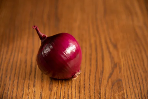 Fresh purple onion on dark wooden background.