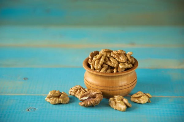 Nueces sobre mesa rústica azul en cuenco de madera — Foto de Stock