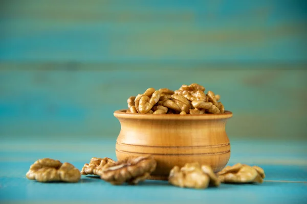 Nueces sobre mesa rústica azul en cuenco de madera — Foto de Stock